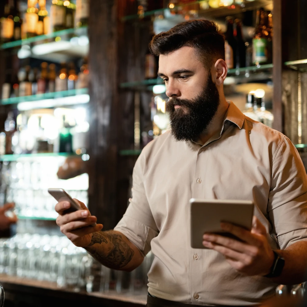 A barman checking POS devices behind a bar