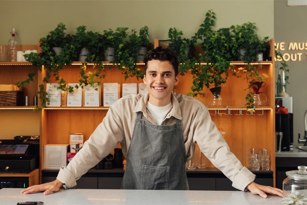 portrait young man behind counter welcoming customers